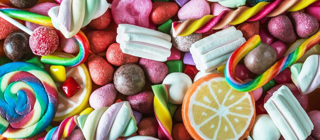 Una variedad colorida de dulces, incluyendo piruletas, gomitas y caramelos, dispuestos en una superficie, ideal para los amantes de los postres y golosinas.
